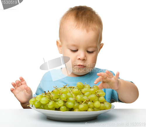 Image of Little boy is eating grapes