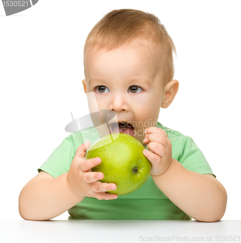 Image of Little child is eating green apple
