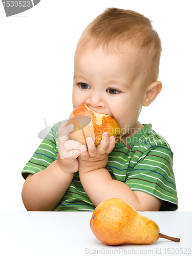 Image of Cute little boy is biting pear