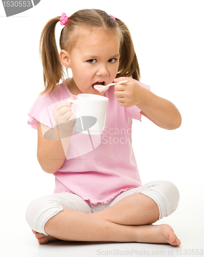 Image of Cute little girl is eating yogurt