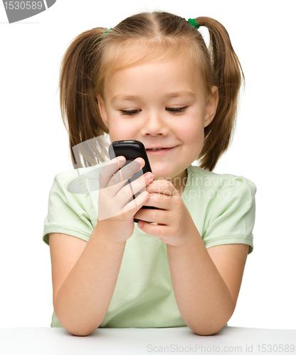 Image of Cute little girl is playing with cell phone