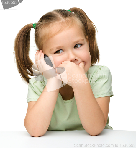 Image of Cute little girl is talking on a cell phone