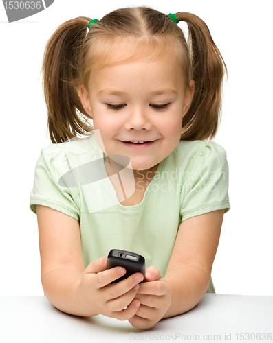 Image of Cute little girl is playing with cell phone