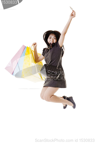 Image of Jumping Chinese woman holding shopping bags and credit card.