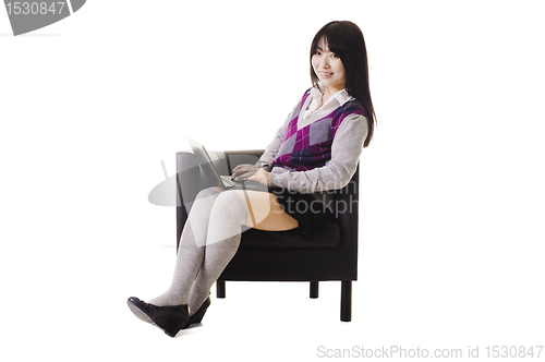 Image of Chinese student working on a laptop and sitting in a chair.