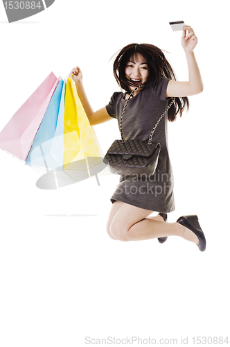 Image of Jumping Chinese woman holding shopping bags and credit card.