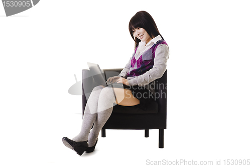 Image of Chinese student working on a laptop and sitting in a chair.