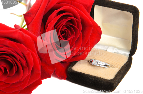Image of Diamond Ring Next to Two Red Roses