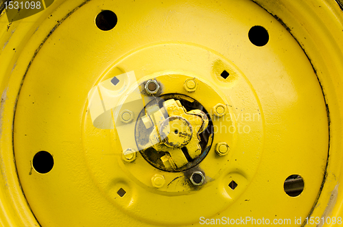 Image of Yellow tractor wheel closeup details bolt nut hole 