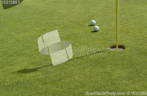 Image of hole and golf balls in green back