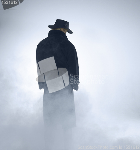 Image of Woman wearing trench coat and standing in fog