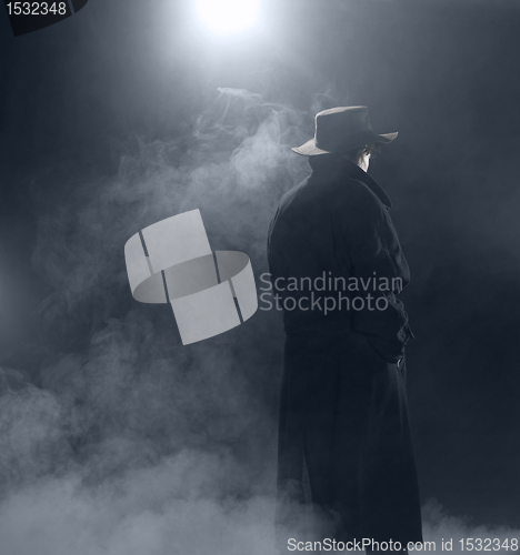 Image of Woman wearing trench coat and standing in fog