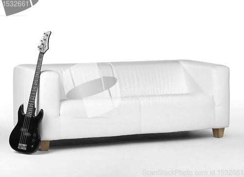 Image of black bass guitar and white couch