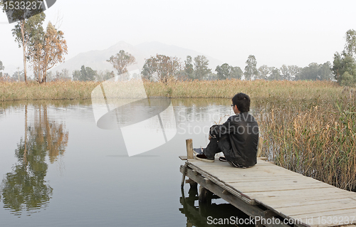 Image of man sitting on a wooden pier