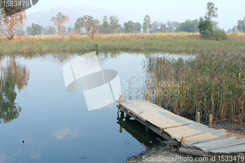 Image of wooden pier in tranquil lake at morning 