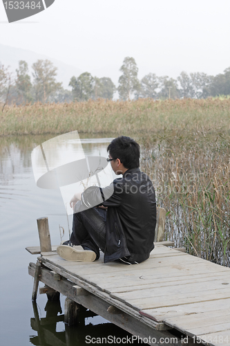 Image of man sitting on a wooden pier