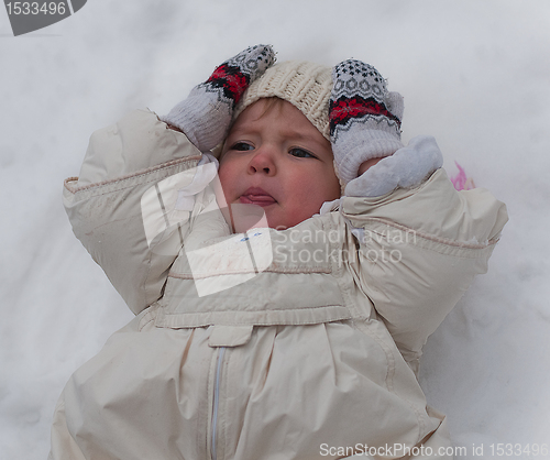 Image of Little girl lays on the snow