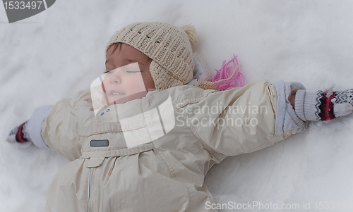 Image of Little girl lays on the snow