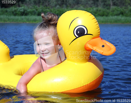 Image of little girl bathes in river in inflatable duck