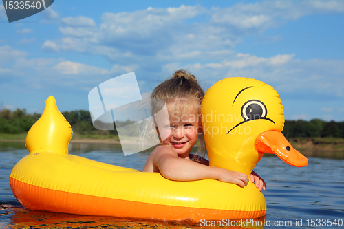 Image of little girl bathes in river in inflatable duck