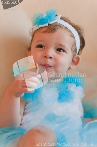 Image of Little girl in the blue dress eats cookie