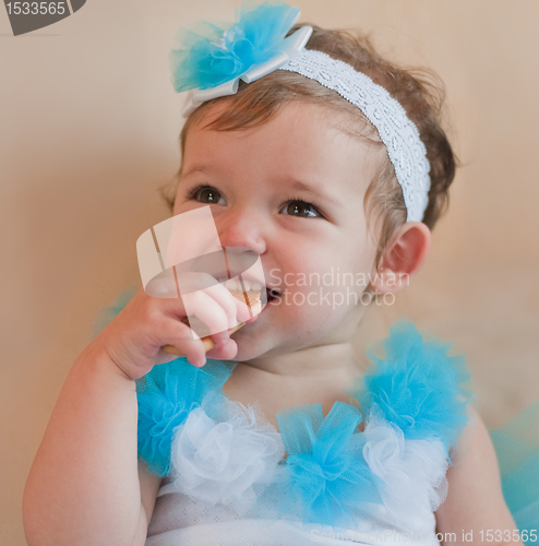 Image of Little girl in the blue dress eats cookie