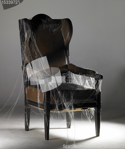 Image of brown wing chair and cobwebs