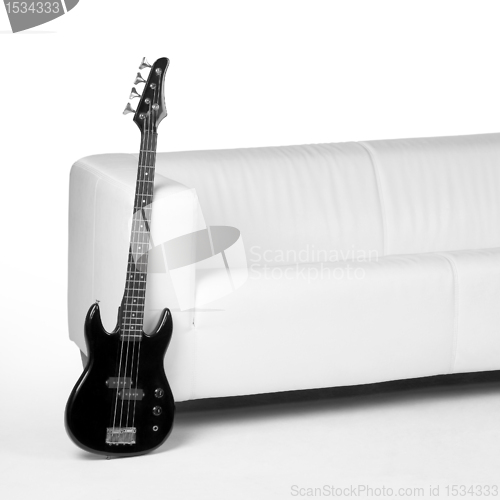 Image of black bass guitar and white couch