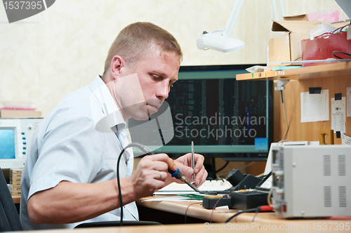 Image of worker soldering microchip scheme