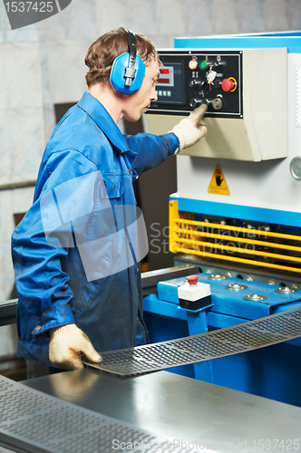 Image of worker operating guillotine shears machine