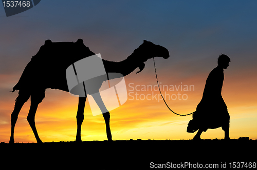 Image of Silhouette of Arab with camel at sunrise