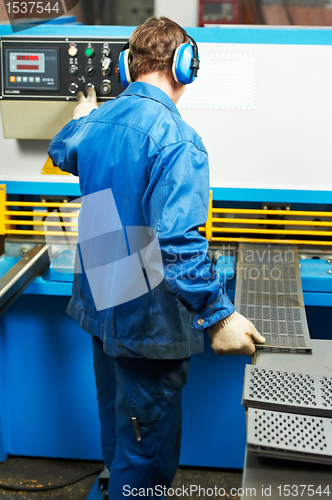 Image of worker operating guillotine shears machine