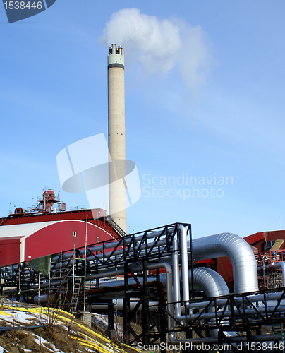 Image of Industrial zone, Steel pipelines and smokestack against blue sky