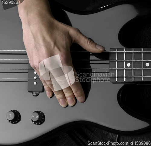 Image of hand on bass guitar