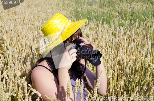 Image of Woman taking shots in field of wheat.