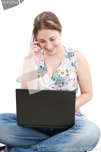 Image of A pretty young woman sitting on floor with laptop and mobile pho