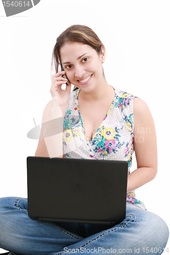 Image of beautiful young woman talking over the phone and using laptop 