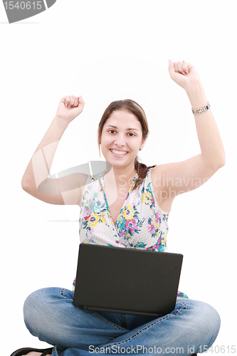 Image of woman with laptop sitting on the floor and celebrating her succe