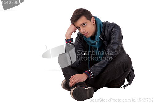 Image of handsome young man, sitting on the floor, thinking