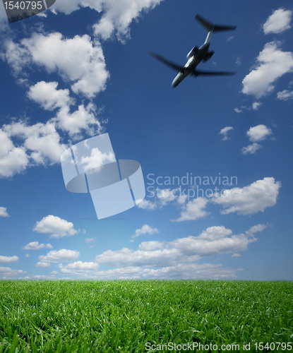 Image of Airplane Flying in a Blue Sky over Green Grass