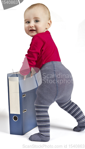 Image of small child standing next to blue ring binder