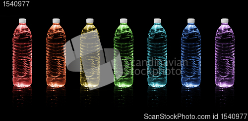 Image of Bottles of drinking water. Rainbow colors on a black