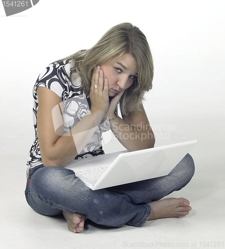 Image of bored girl sitting on the floor with white laptop