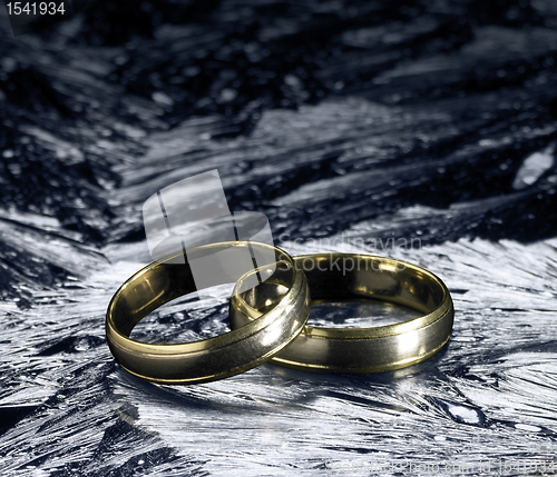 Image of two golden wedding rings on ice surface