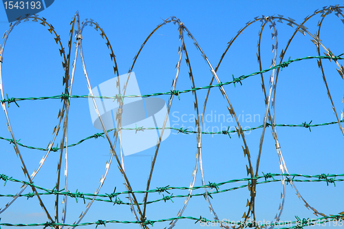 Image of barbed wire against blue sky 