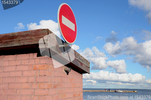 Image of Road sign brick on building. Pier and sea distance 