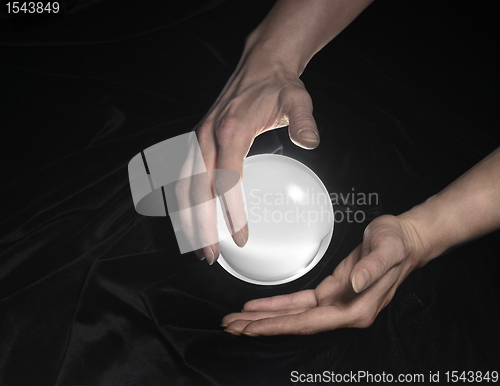 Image of crystal ball and hands around