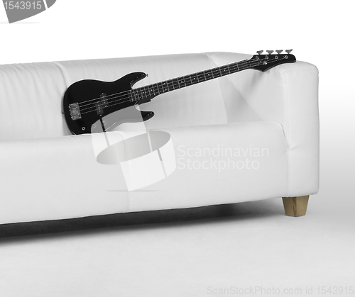 Image of black bass guitar on white couch