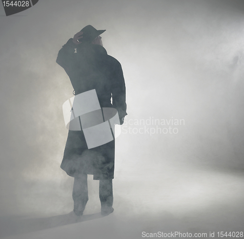 Image of Woman wearing trench coat and standing in fog