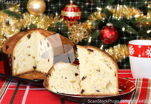 Image of Panettone, whole and sliced, in front of a festive Christmas tre
